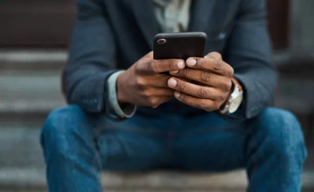 cropped shot of a businessman using a smartphone against an urban background