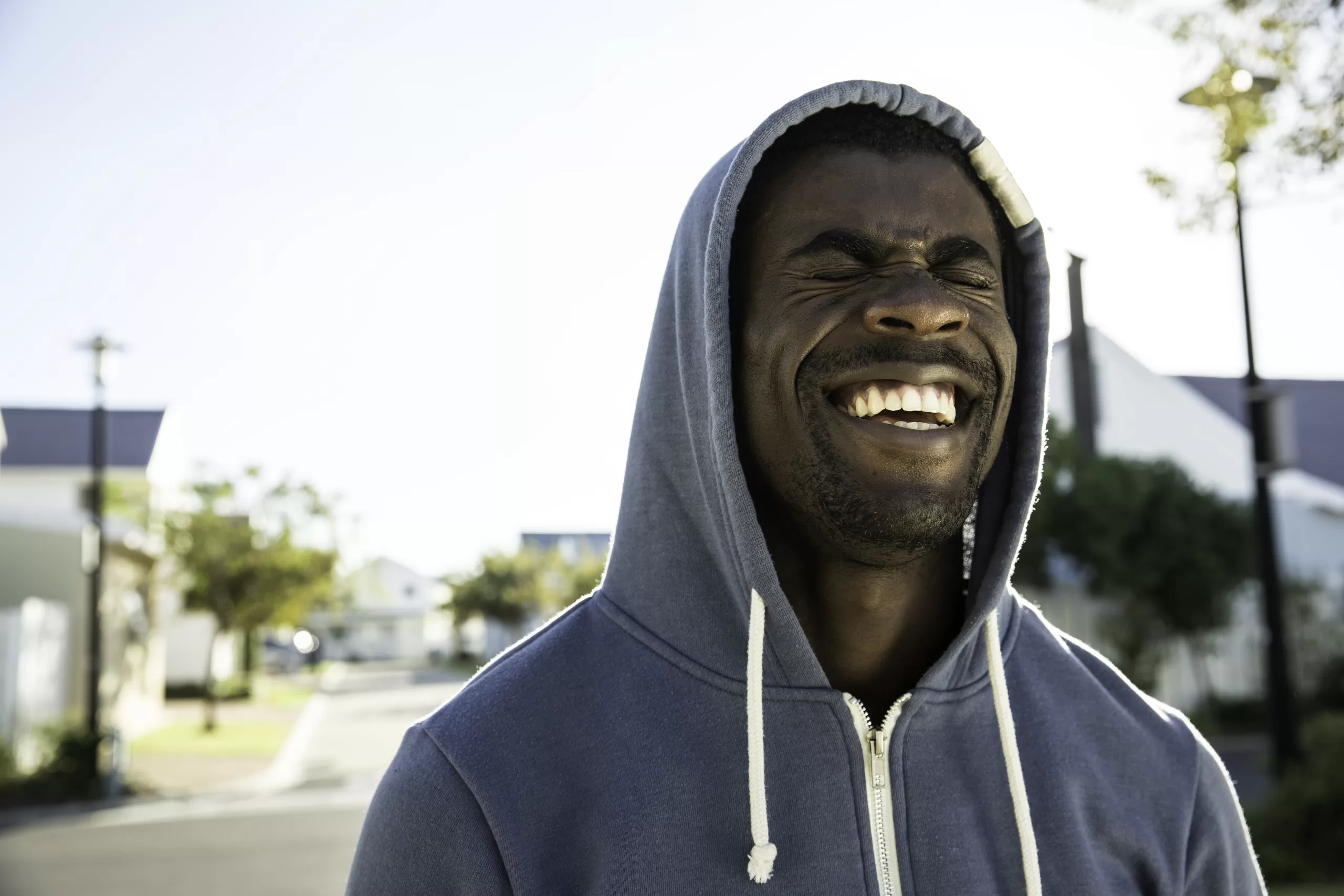 portrait of man wearing hooded top eyes closed laughing